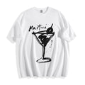 Flat lay product photography of a crisp white t-shirt highlighting a high-contrast black brush-stroke martini line art print and the word 'Martini' written above it.