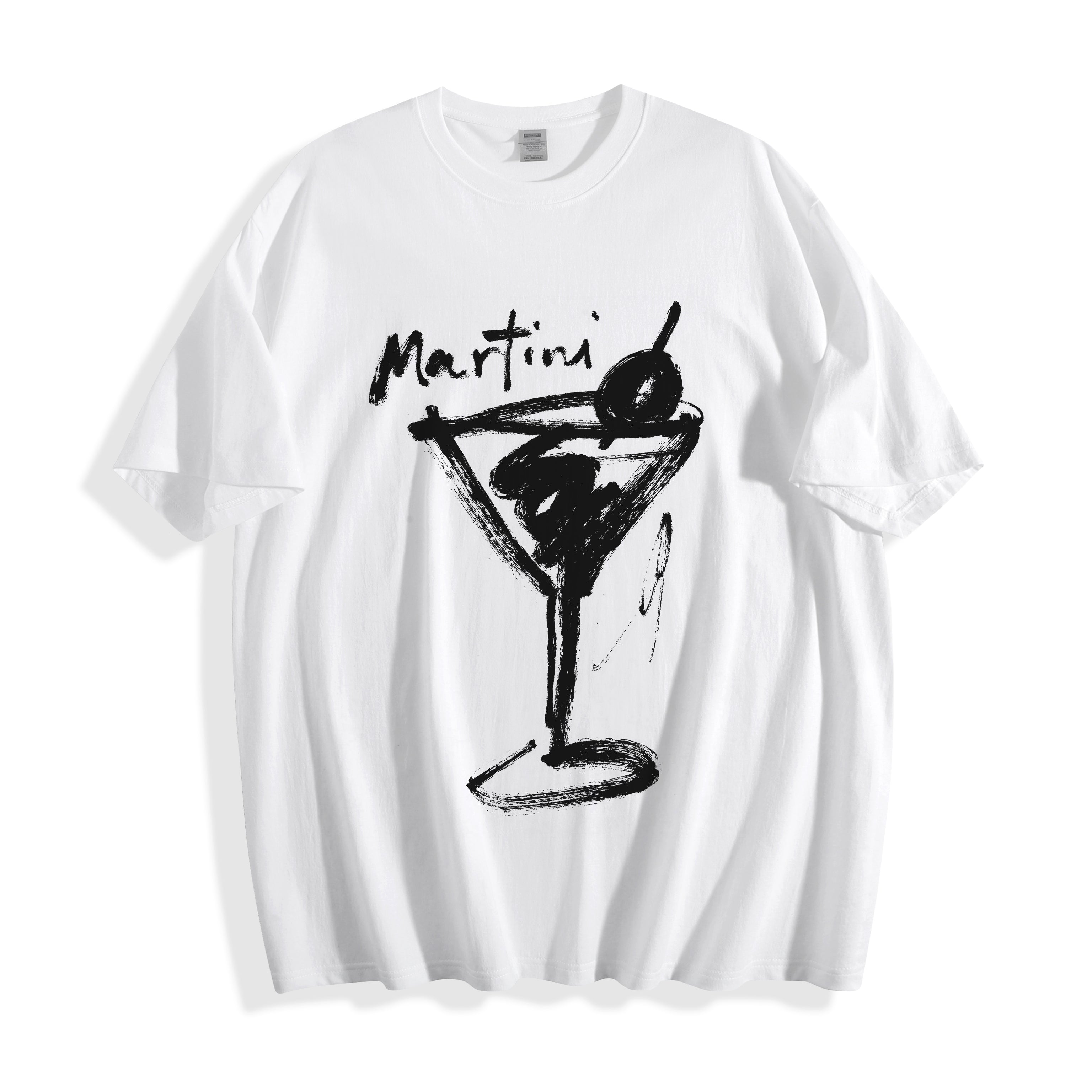 Flat lay product photography of a crisp white t-shirt highlighting a high-contrast black brush-stroke martini line art print and the word 'Martini' written above it.