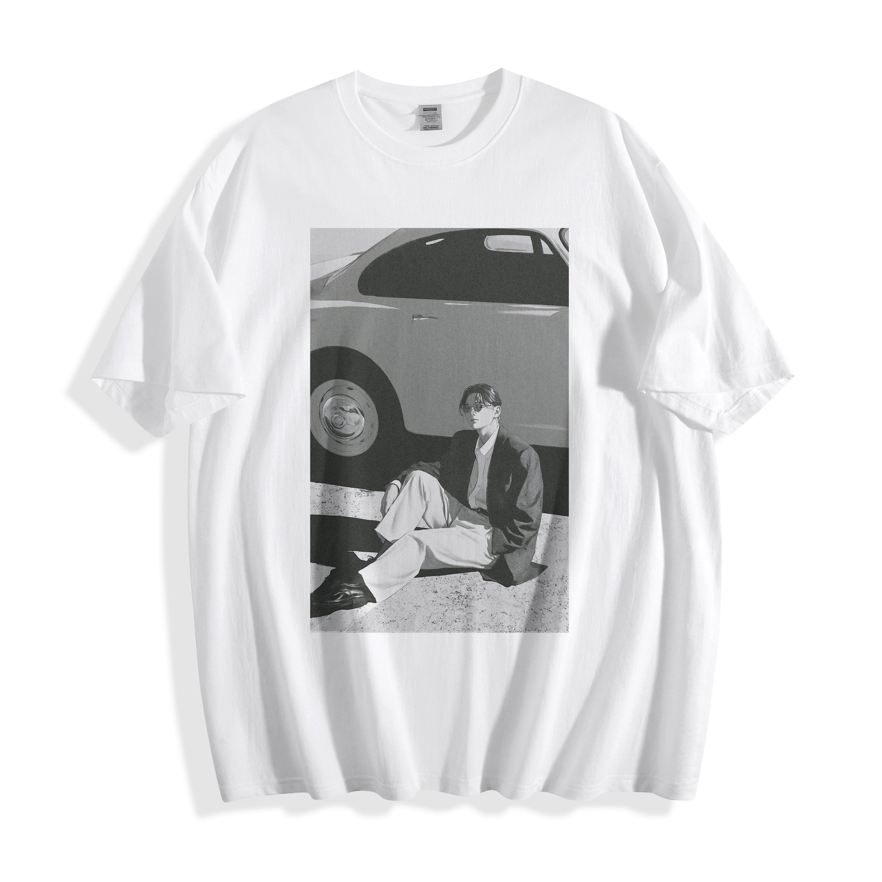 A white short-sleeve crewneck t-shirt featuring a black and white 90s cinematic print on the front of a man sitting next to a vintage car.