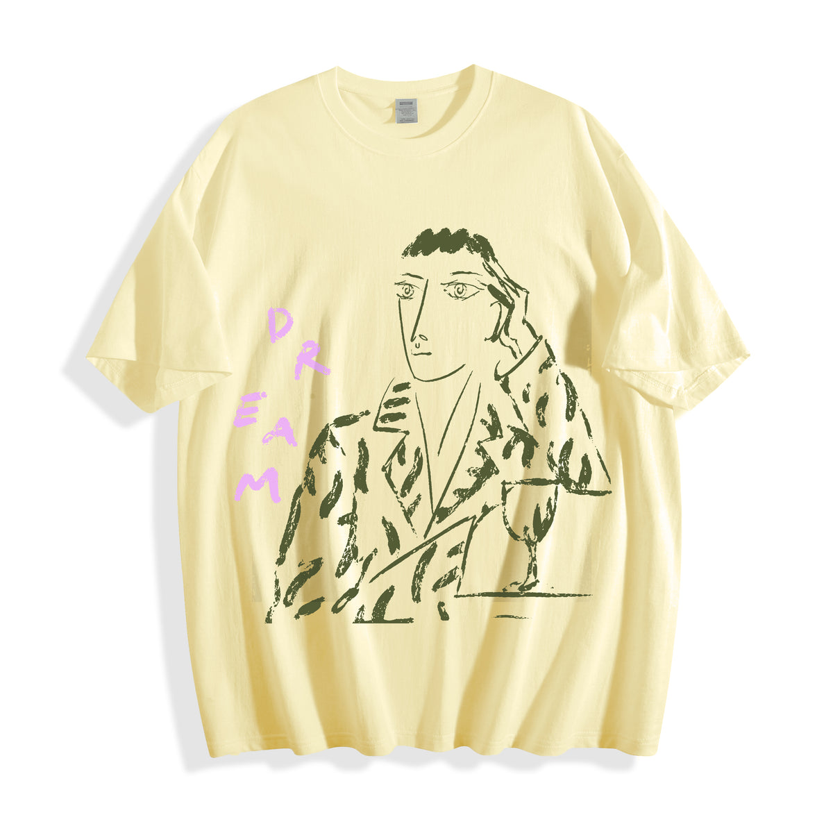 A pale yellow short-sleeve t-shirt with a graphic print of a stylized face in black and green, accompanied by the text 'DREAM' in pink on the left side, displayed on a clean white background.